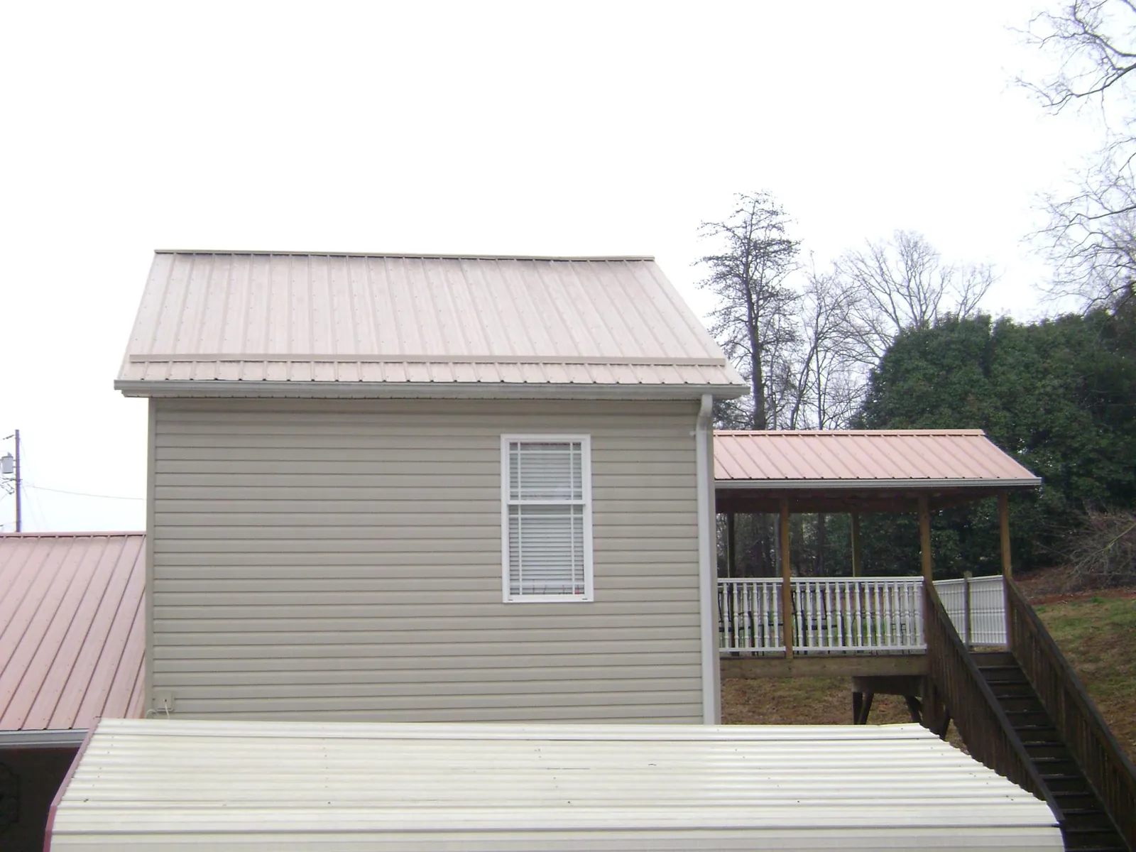 Tan metal roofs on a two story addition and attached porch, from a Roof Replacement job in Palmetto